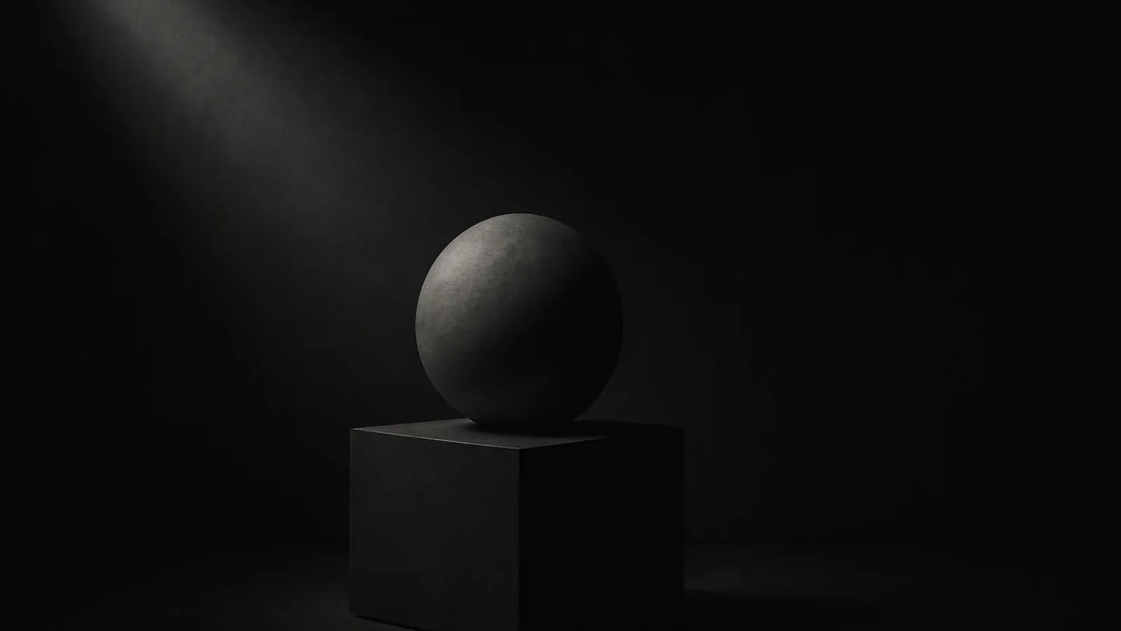 A stone sphere half-carved out of darkness by a single shaft of light in an empty gallery.