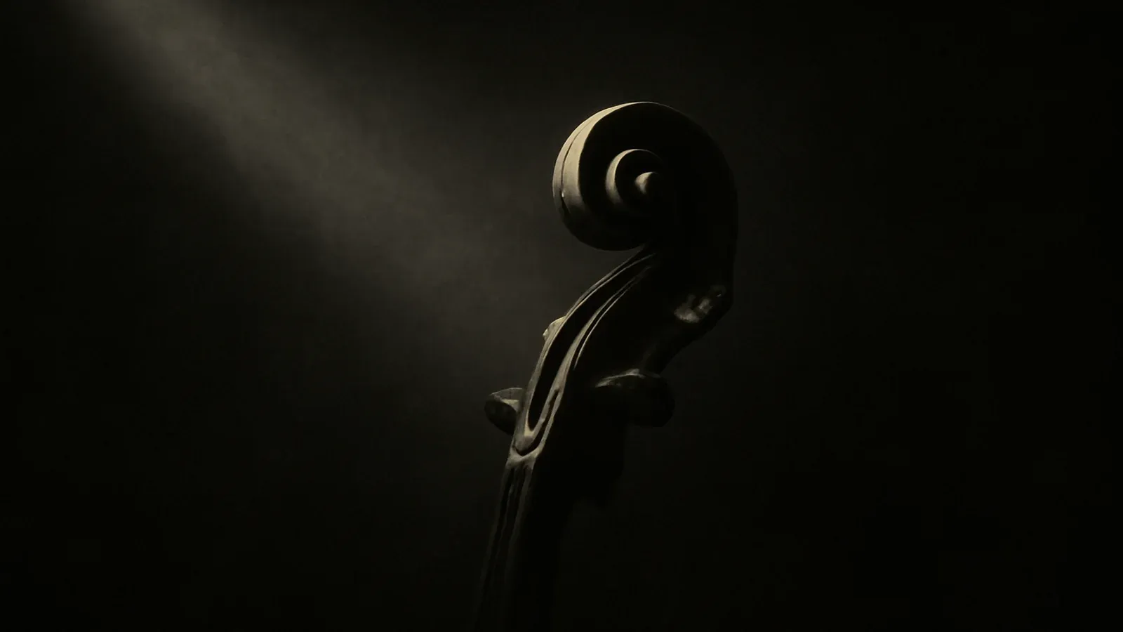 A violin scroll curling out of deep shadow, caught by a single shaft of light.